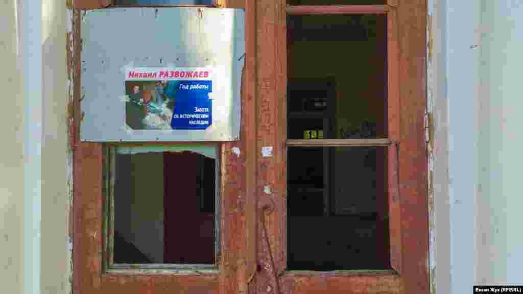 «Забота об историческом наследии» – гласит реклама, наклеенная на дверь с выбитыми стеклами