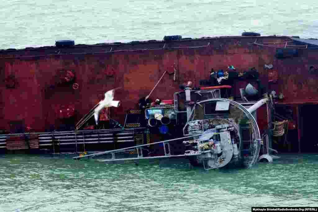 Половина судна занурена у воду, правий борт впирається в хвилеріз 