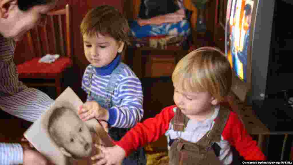 Дети Ивана Яцкина рассматривают детскую фотографию отца. Дома в Крыму Ивана ждут четверо детей, а совсем скоро на свет появится и пятый ребенок. Как живет семья Ивана Яцкина без отца, сына и мужа – смотрите в нашей фотогалерее