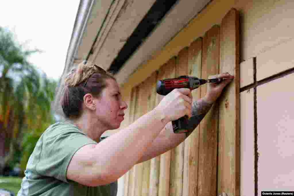 Жінка забиває дошками вікна свого будинку перед наближенням урагану «Мілтон» у Санкт-Петербурзі, штат Флорида, США, 8 жовтня 2024 року