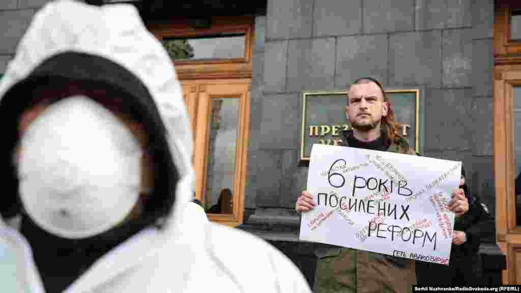 Активіст тримає у руках плакат із іронічним написом «6 років посилених реформ»