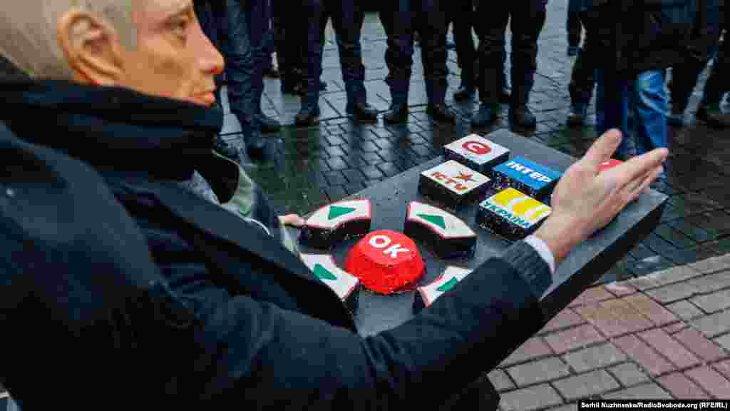 Учасники акції провели перфоманс – активіст, одягнений у маску Путіна, сидів на стільці з великим пультом, де були написані назви українських телеканалів