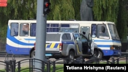 Правоохоронці лежать на землі за автомобілем біля пасажирського автобуса, захопленого зловмисником у Луцьку, 21 липня 2020 року