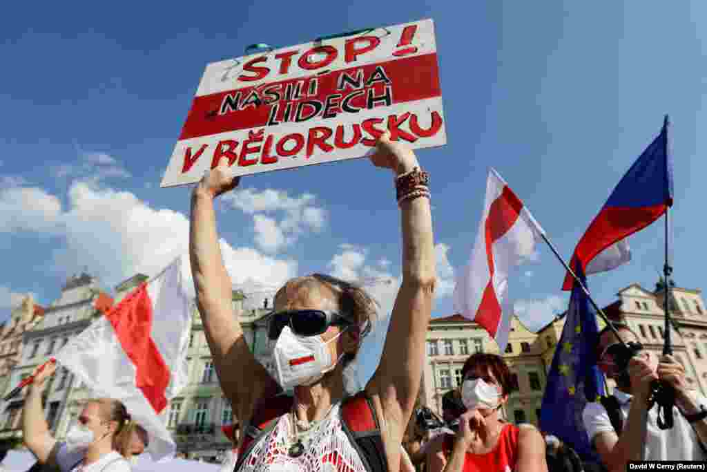 Учасниця акції тримає в руках плакат із написом чеською мовою: «Припиніть насильство над людьми у Білорусі»