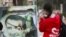 A woman uses her mobile phone near a damaged picture of Syrian President Bashar al-Assad as people celebrate, in Qamishli