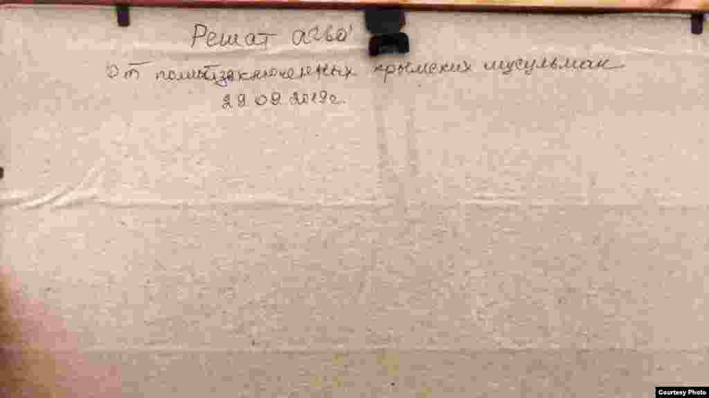 На обратной стороне картины написано: «Решат агъа! От политзаключенных крымских мусульман. 29.09.2019». Решат Эмирусеинов – отец Рустема Эмирусеинова, осужденного на 17 лет за «организацию деятельности террористической организации»