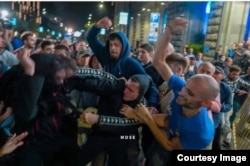 ამ კადრში ალექსანდრე მუკათარიძე "ოცნების" ლურჯი მაისურით ორ სხვა პირთან ერთად უსწორდება დემონსტრანტს.