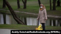 Жінка у медичній масці у парку та Троєщині в Києві, 24 квітня 2020 року