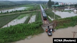 Kim Jong Un hoda uz nasip prema vozu za vrijeme posjete poplavljenom području blizu granice s Kinom, sjevernokorejska provincija Pjongan, 31. jula 2024.