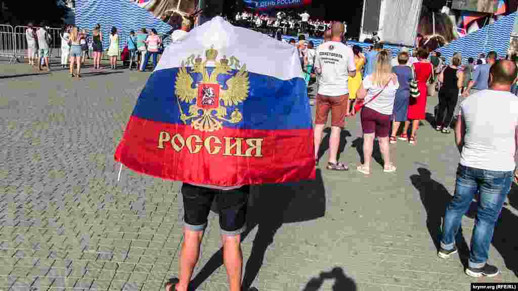 Один из зрителей закрылся российским флагом от палящего солнца  