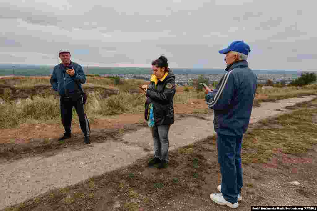 Гора  Кременець – найвища точка Ізюму, з телевежею та монументом на честь загиблих у Другій світовій війні. На Кременці завжди є скупчення людей: це єдине місце в Ізюмі, де вдавалося тоді зловити мобільний зв’язок, вересень 2022 року / Праворуч: початок жовтня 2024-го  Тепер у місті все добре з мобільним звʼязком, і люди просто приїжджають на гору дивитись на заходи сонця  