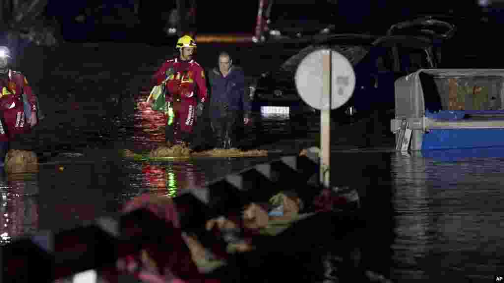 Žena, u pratnji vatrogasaca, hoda kroz poplavljene ulice u Valenciji, 30. oktobra 2024. 