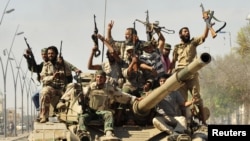 Повстанцы, воевавшие против армии Муаммара Каддафи, празднуют его смерть и падение его последнего оплота – города Сирт. 20 октября 2011 года