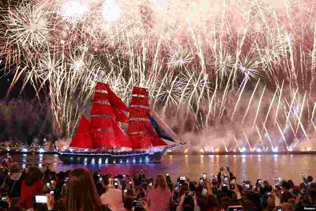 Зрители наблюдают за фейерверками в небе и бригом "Россия" с алыми парусами, плывущим по Неве во время празднеств в честь выпускников школ, Санкт-Петербург, Россия, 29 июня 2025 года. REUTERS/Антон Ваганов