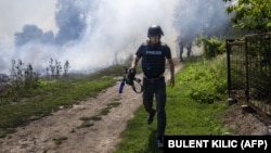 На передньому плані журналіст AFP, а позаду піднімається дим після обстрілу. Донеччина, 31 липня 2022 року