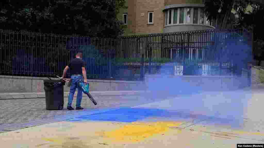 Мъж почиства остатъците от материал с украинските цветове, разпръснат по тротоара пред руското посолство във Вашингтон, САЩ, август 2025 г.