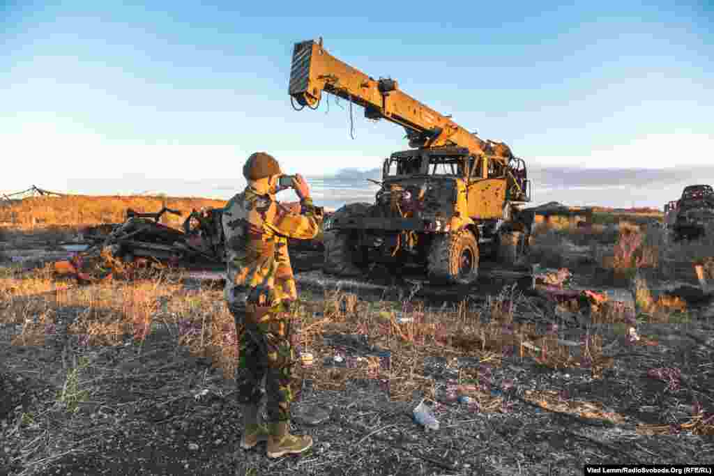 Волонтер Юрій фотографує кран, зруйнований від обстрілів
