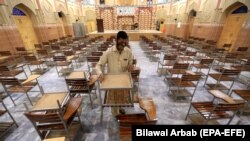 یو چپړاسي د پېښور یوې تعلیمي ادارې امتحاني مرکز کې تر هغه وروسته صفايي کوي چې حکومت د مارچ پر ۱۵ د ځینو ضلعو د سکولونو تړلو اعلان وکړ. ۲۰۲۱، د مارچ ۱۵مه نېټه