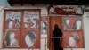 A woman wearing a niqab enters a beauty salon where the ads of women have been defaced in Kabul.