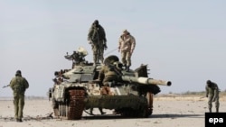 Боевики группировки «ДНР» исследуют поврежденный танк в разрушенном аэропорту Донецка. 13 октября 2015 года