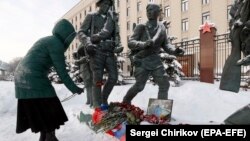 Жінка кладе квіти біля портрета загиблого російського пілота Романа Філіпова поблизу Міністерства оборони Росії, Москва, 6 лютого 2018 року