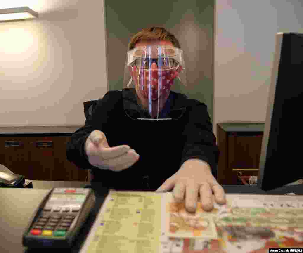 Касир в інформаційному центрі Празького граду в масці із захисним екраном