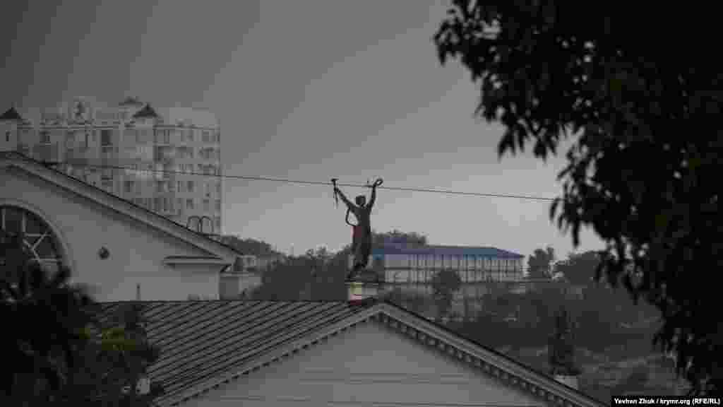 На фоне потемневшего неба – фигура Мельпомены с лавровым венком в одной руке и веером в другой