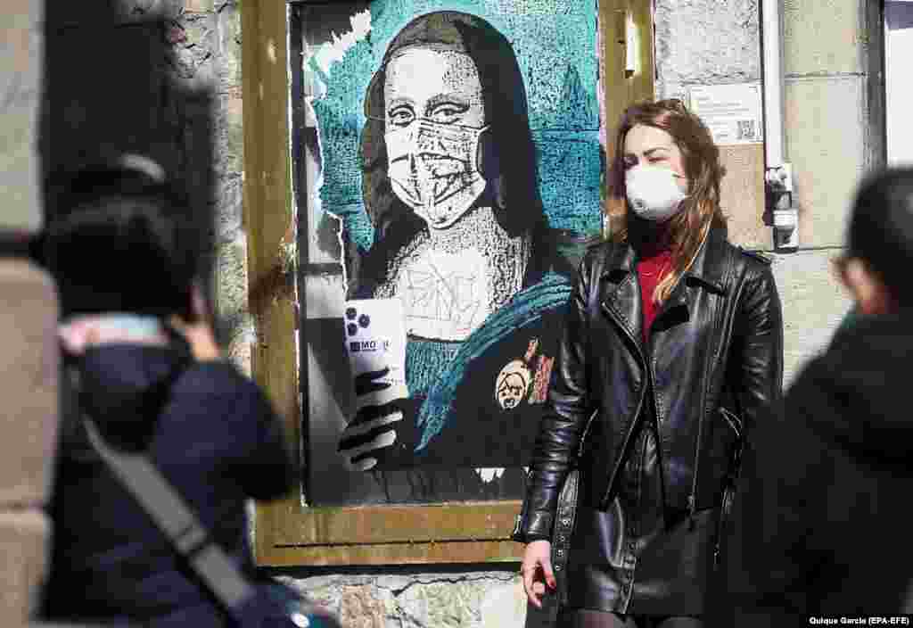 Туристка в Барселоні позує для фото поруч із графіті, на якому зображена Мона Ліза в масці під назвою «Вірус мінливого світу». Іспанія. Весна 2020 року