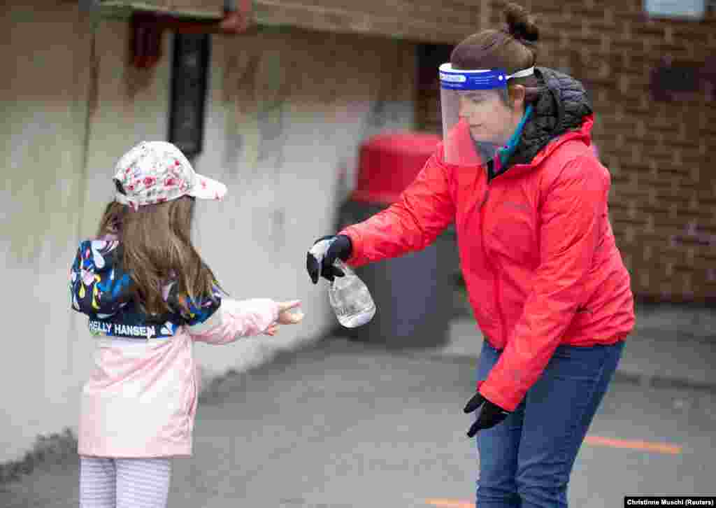 Школярка дезінфікує руки на шкільному подвір’ї в канадському місті Сен-Жан-сюр-Рішельє у провінції Квебек 11 травня 2020 року. Школи поза межами найбільшого міста провінції Монреаля й околиць знову відкрилися після карантину, пов’язаного за спалахом коронавірусу