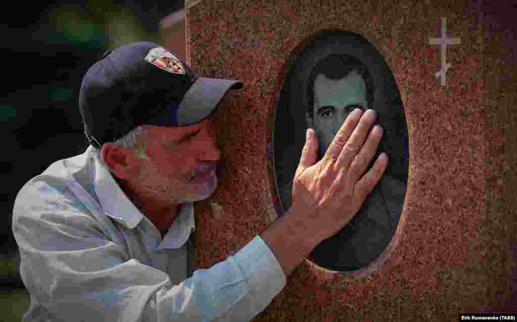 Мужчина скорбит на кладбище, где похоронены жертвы теракта в школе в городе Беслан в 2004 году, 1 сентября   