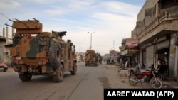 Turkish military vehicles drive in a convoy headed for the south of Idlib Province as they pass by the town of Atareb on February 3.