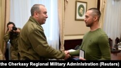 Голова Черкаської обласної військової адміністрації Ігор Табурець (ліворуч) вручає нагороду Роману Грибову, українському військовослужбовцю, автору відомої фрази «Русский военный корабль, иди нах*й». Черкаси, 29 березня 2022 року