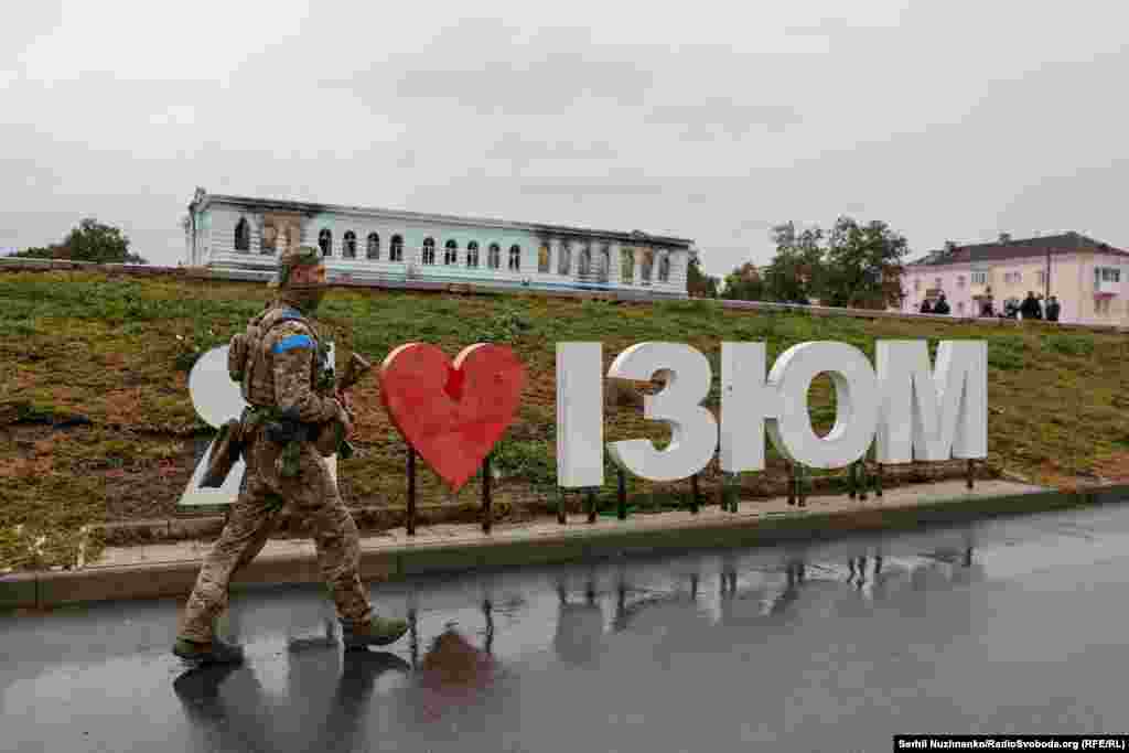 Український військовий у звільненому Ізюмі, вересень 2022 року / Праворуч: початок жовтня 2024-го В Ізюмі працюють комунальні служби, державні установи, гуманітарні організації, ринки, магазини, військторг і спортзал. Але більшість підприємств, що були розбиті обстрілами й розкрадені  мародерами, так і не відновили роботу. Багато його колишніх працівників теж виїхали з міста «Виживаємо коштом бюджетників, і військових»,  говорять місцеві жителі  