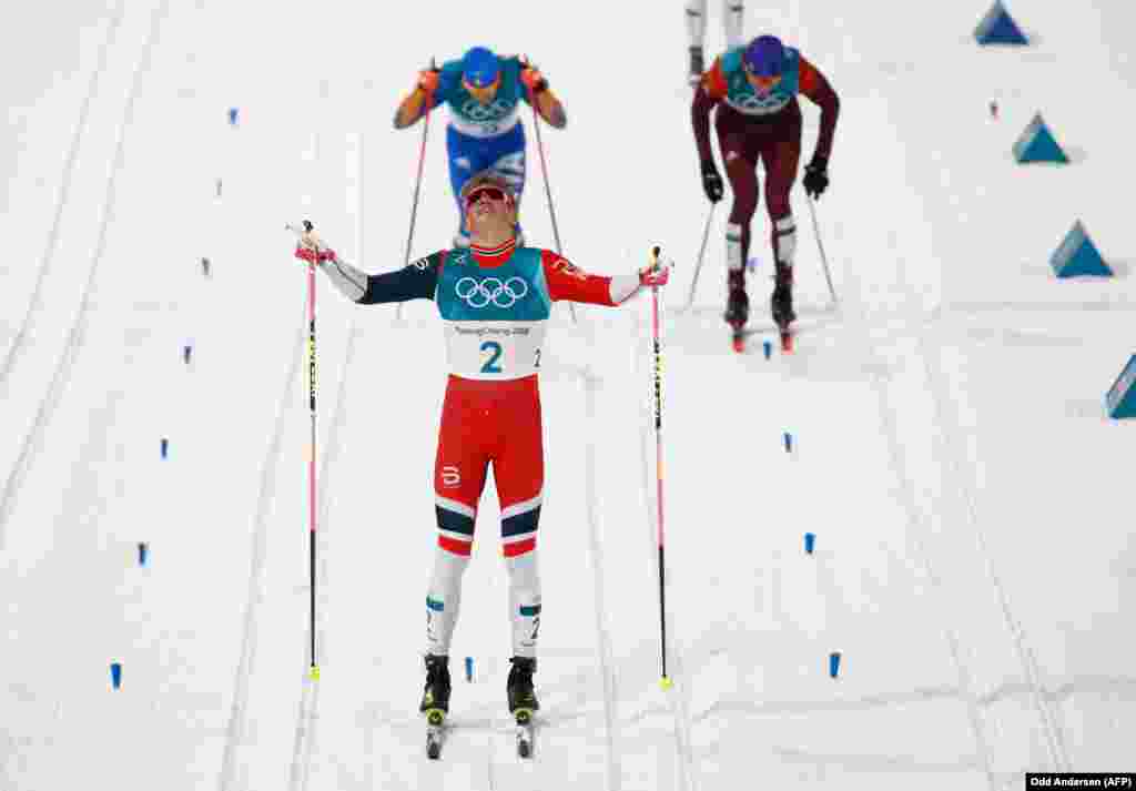 Бег на лыжах: норвежец Йоханнес Гесфлот клеб (в центре) празднует победу, пересекая финишную линию – он завоевал золото. Серебряную позицию занял итальянец Федерико Пеллегрини (слева позади). Александр Большунов из России получил третье место в мужском финале классического лыжного бега