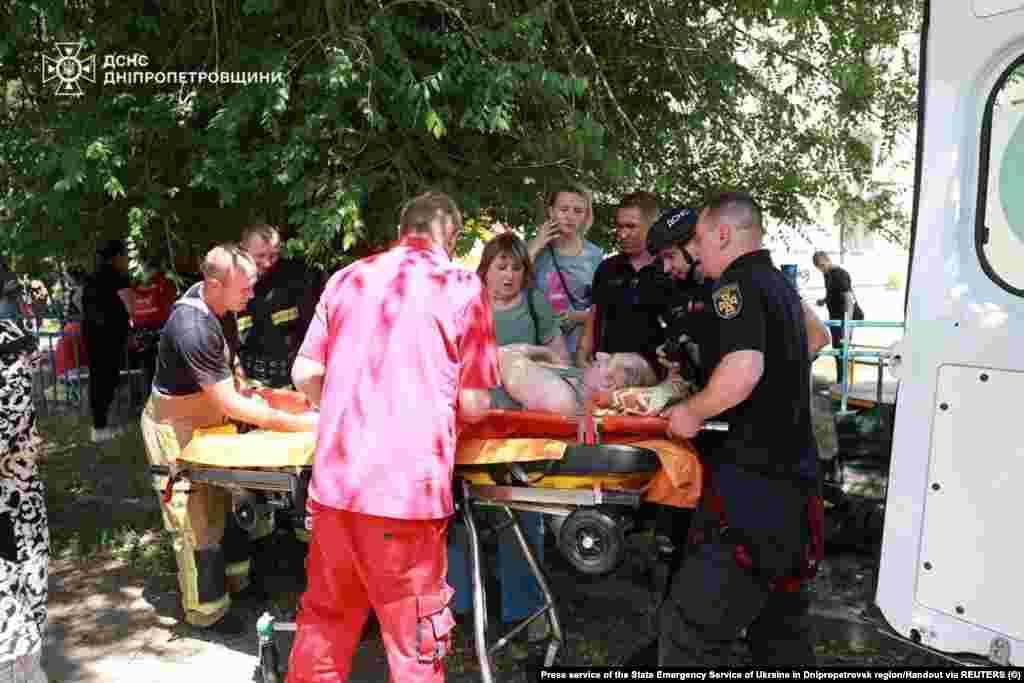 Чоловіка, який зазнав поранень під час російського ракетного удару, несуть в машину швидкої допомоги, Дніпропетровська область, 24 червня 2025 року