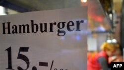 A sign in a restaurant window shows the price of a hamburger in outgoing Estonian kroons and euros.