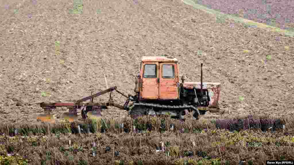 За рекой на поле «отдыхает» трактор
