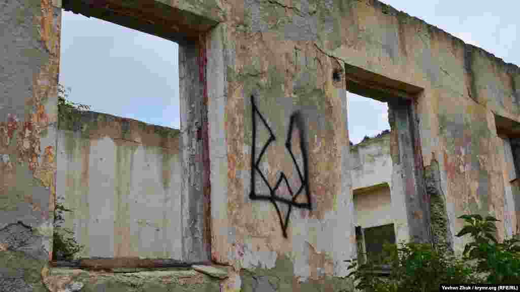 А этот стилизованный украинский герб – трезубец – кто-то нарисовал на развалинах здания бывшей воинской части возле все того же пляжа.  Корреспондент Крым.Реалии прошел по дороге на «Васили» и запечатлел все на фото