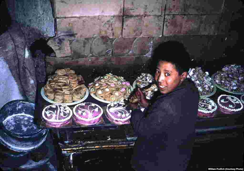 A boy decorates cakes, cookies, and other sweets.