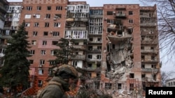 Украинский военный на фоне разрушенного при обстрелах жилого дома в Покровске (Донецкая область)