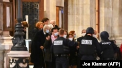 Люди виходять із Віденської опери під захистом озброєних поліцейських після нападів у центрі австрійської столиці. 2 листопада 2020 року