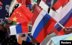 Глядачі махають російськими, китайськими та іншими прапорцями під час червневої церемонії в центрі Москви з нагоди початку 100-денного відліку до конкурсу «Інтербачення», запланованого на 20 вересня 2025 року