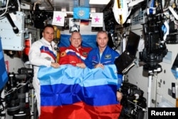 Російські космонавти Олег Артем’єв, Денис Матвєєв і Сергій Корсаков позують із прапором угруповання «ЛНР» на Міжнародній космічній станції (МКС). 4 липня 2022 року.