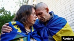 Un prizonier de război ucrainean își îmbrățișează soția în timp ce se întoarce acasă după prima etapă a unui schimb de prizonieri cu Rusia, care a început pe 23 mai.