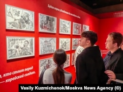 Відвідувачі розглядають пропагандистські малюнки, на яких зображено північнокорейських військових, які воюють проти України.