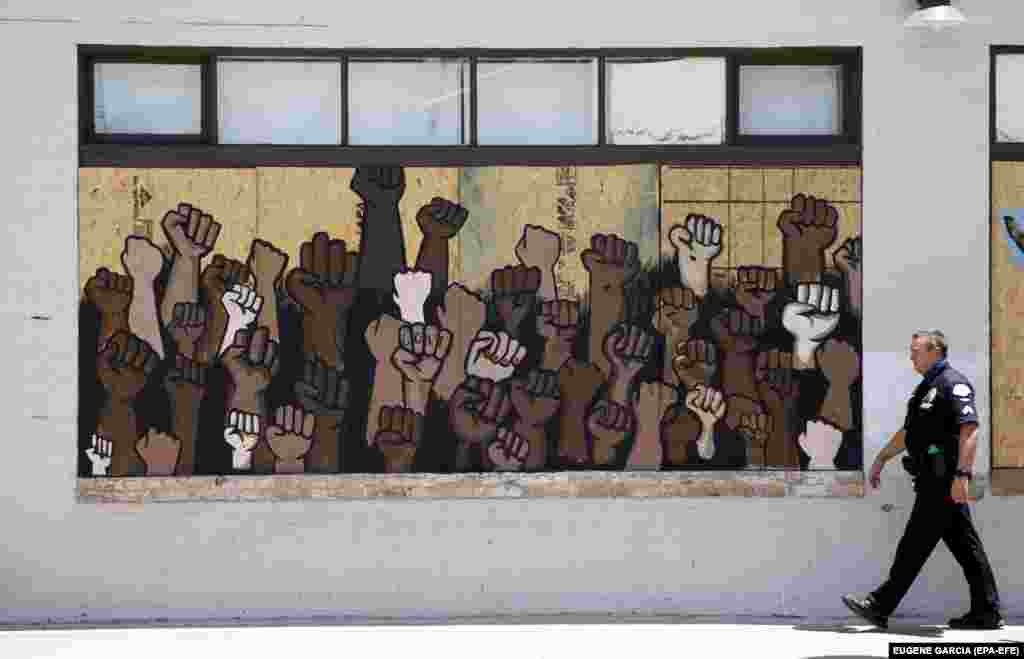 Полицейский идет мимо граффити в поддержку движения Black Lives Matter ("Черные жизни важны") в Лос-Анджелесе