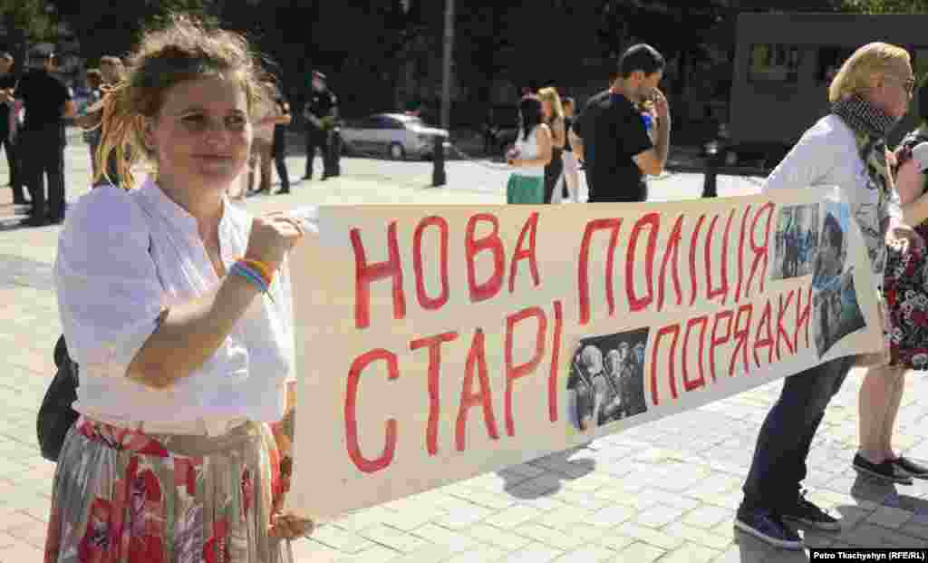 Учасниця протесту проти Національної поліції тримає в руках плакат: «Нова поліція – старі порядки»