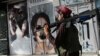 A Taliban fighter walks past a beauty salon with images of women defaced using spray paint in Kabul on August 18, days after the militant group seized the Afghan capital.