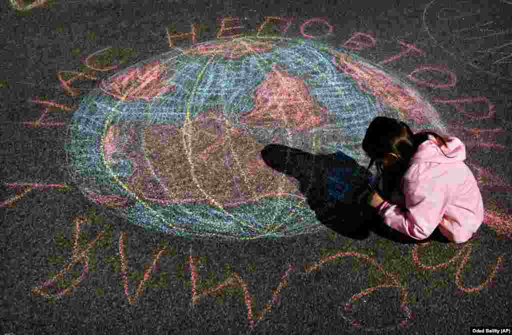 Дитина допомагає намалювати крейдою Землю під час громадського екологічного проєкту в міжнародний День Землі в Києві, 22 квітня 2006 року 