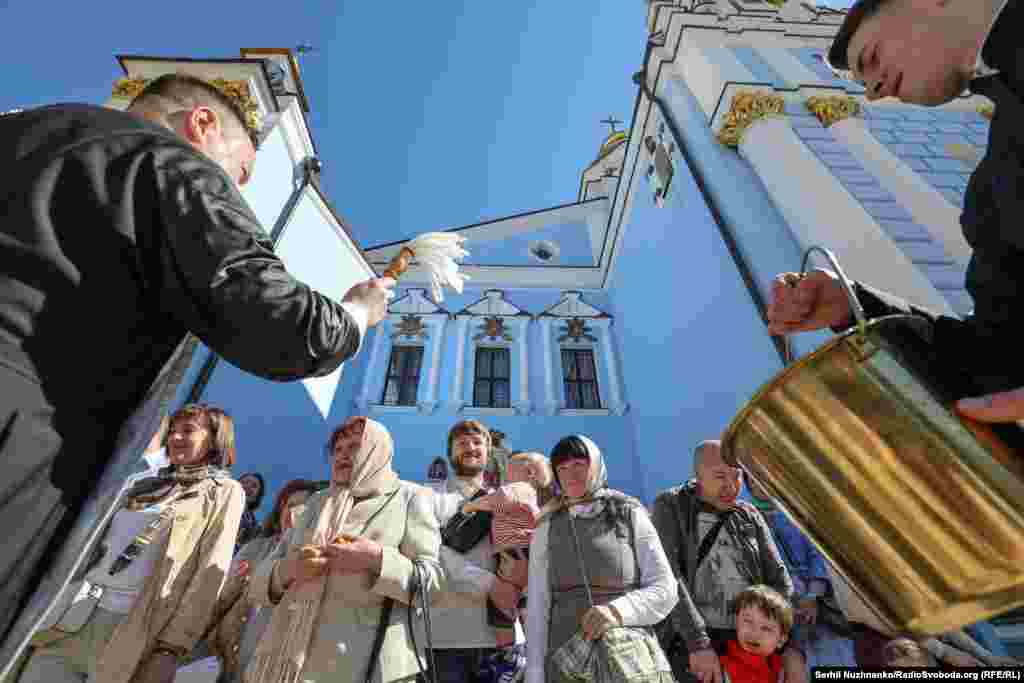 Священник окропляє вірян та їхні великодні кошики святою водою